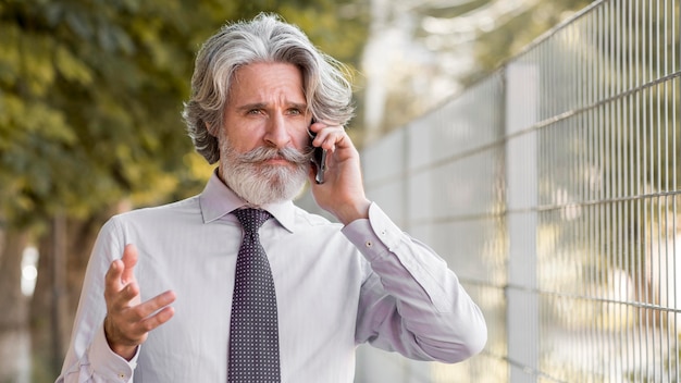 Foto gratuita ritratto del maschio maturo alla moda parlando al telefono