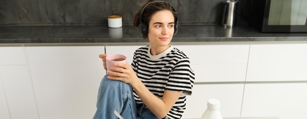 Free photo portrait of stylish modern woman in headphones listens music and drinks tea eats cereals with milk