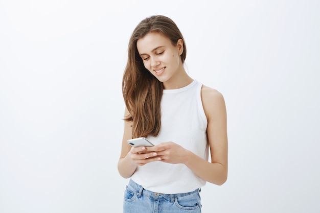 Портрет стильной современной молодой девушки с помощью смартфона и счастливой улыбки