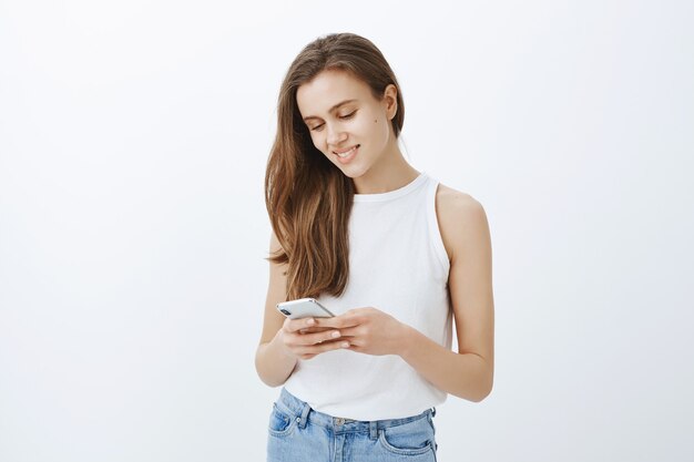 Portrait of stylish modern young girl using smartphone and smiling happy