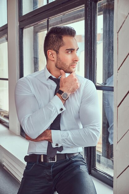Portrait of stylish muscular man sits near the window.