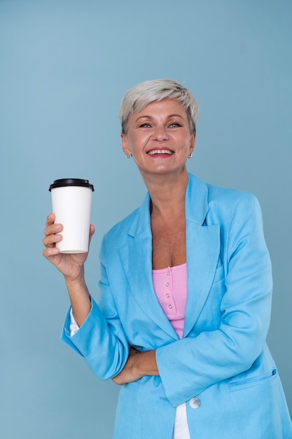 Foto gratuita ritratto di donna senior alla moda che tiene una tazza di caffè