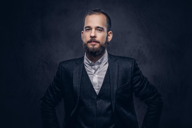 Portrait of a stylish serious bearded male, wearing an elegant suit on a dark background.