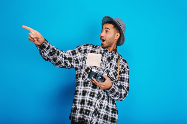 Portrait stylish surprised handsome guy with camera, map, in hat having fun. Travelling, enjoying vacation, weekends, expressing positivity, journey.