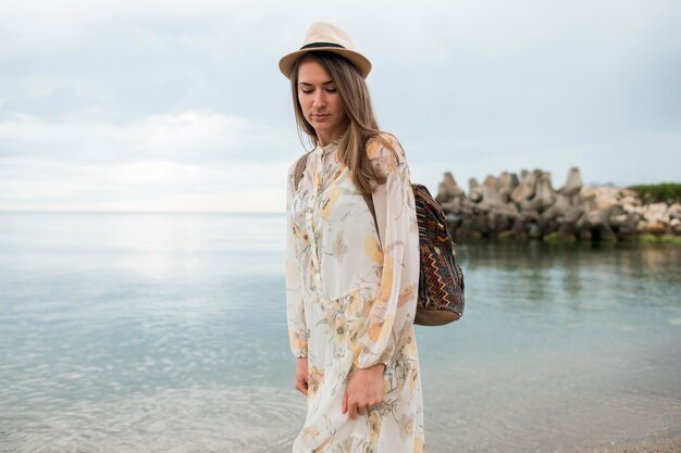 Portrait of stylish traveller walking down the shore