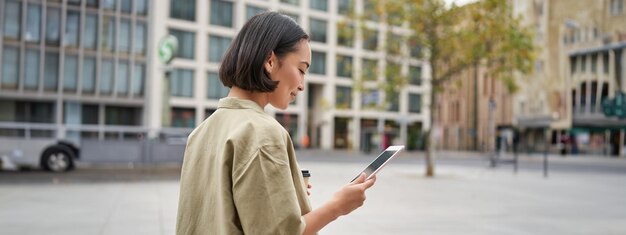 Free photo portrait of stylish urban girl walks in city with tablet drinks takeaway coffee