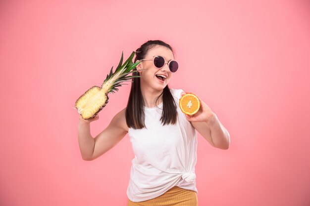 portrait of a stylish woman on pink with fruit in her hands.