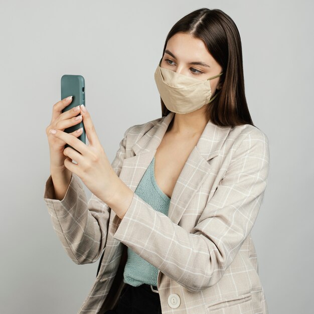 Портрет стильной женщины с маской с помощью мобильного телефона