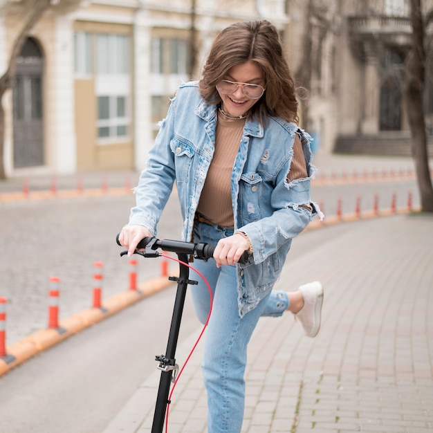 Portrait of stylish young girl riding electric scooter