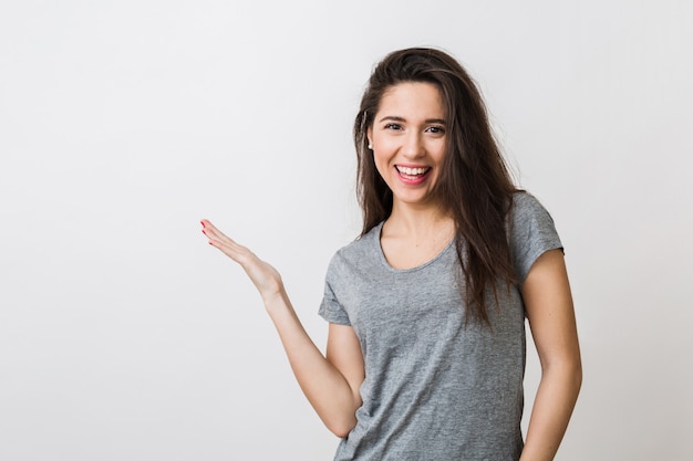 Portrait of stylish young pretty woman smiling in grey t-shirt on , isolated, pointing hand aside, copyspace, happy, positive mood
