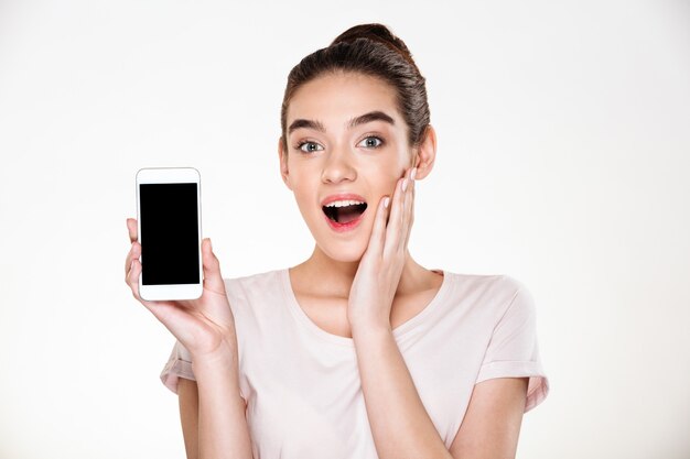 Портрет успешной брюнетки женщины радуясь ее новый современный показ смартфона