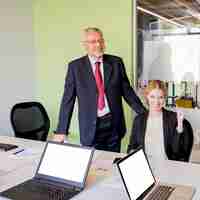 Free photo portrait of a successful mature businessman and businesswoman at workplace