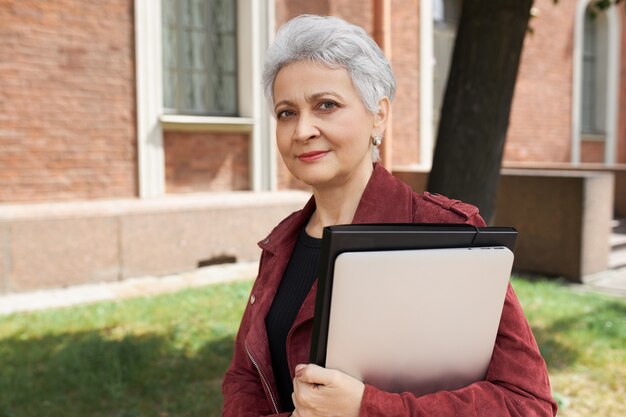 Portrait of successful mature businesswoman in stylish clothes posing outdoors