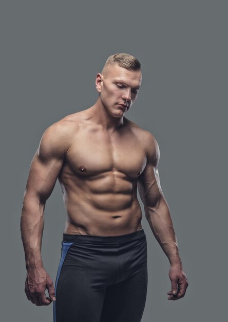 Portrait of suntanned shirtless fitness female isolated on a grey background.