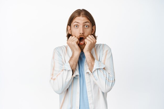 Portrait of surprised bearded blond guy, say wow, gasping and looking excited, watching something amazing, look with impressed face on white.