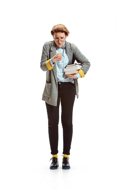 Portrait of a surprised female student holding books isolated on white wall