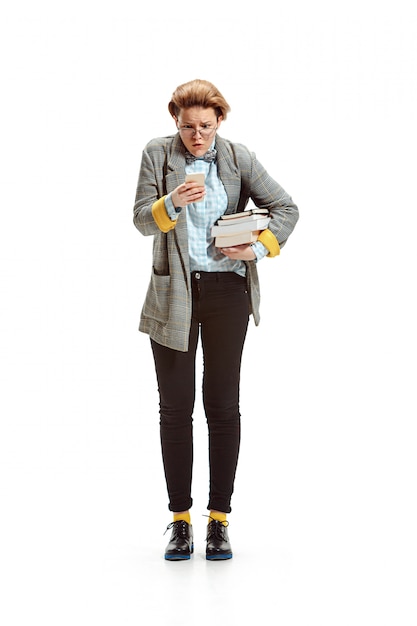 Portrait of a surprised female student holding books isolated on white wall