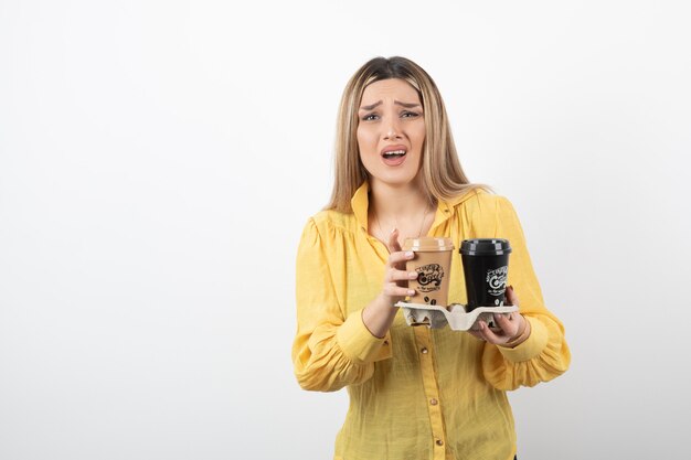 Portrait of surprised girl posing with cups of coffee on white.