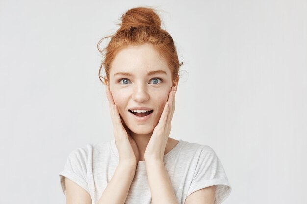 Portrait of surprised happy woman with foxy hair and freckles.