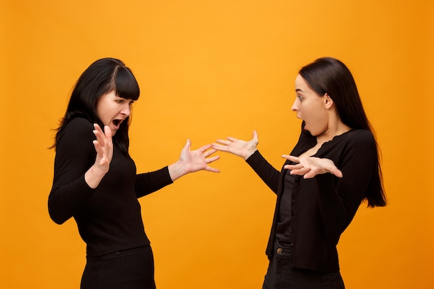 Free photo portrait of a surprised mother and daughter at studio on gold background. trendy colors. human positive emotions and facial expressions concept.