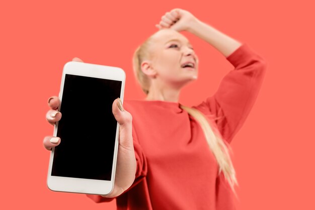 Free photo portrait of a surprised, smiling, happy, astonished girl showing blank screen mobile phone