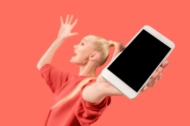 Portrait of a surprised, smiling, happy, astonished girl showing blank screen mobile phone