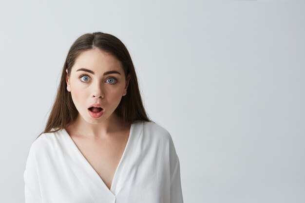 Portrait of surprised young beautiful businesswoman with opened mouth .