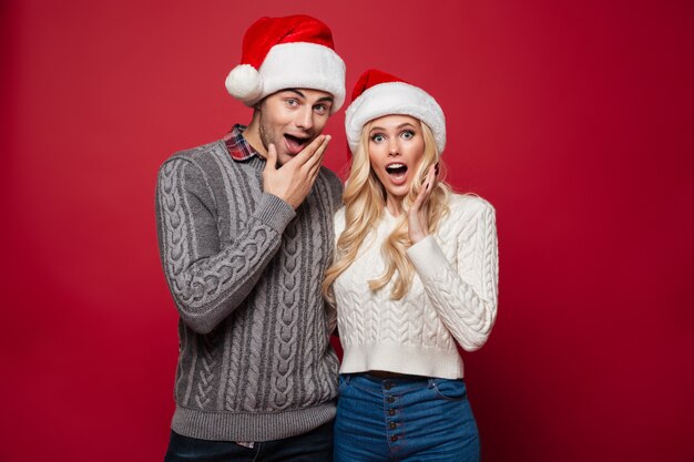 Portrait of a surprised young couple in christmas hats