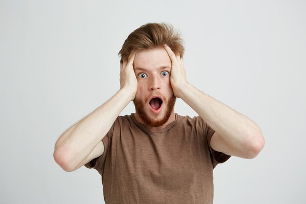 Portrait of surprised young handsome man with beard. Opened mouth.