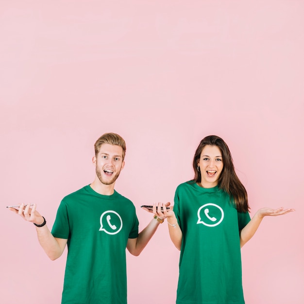 Free photo portrait of surprised young man and woman with smartphone