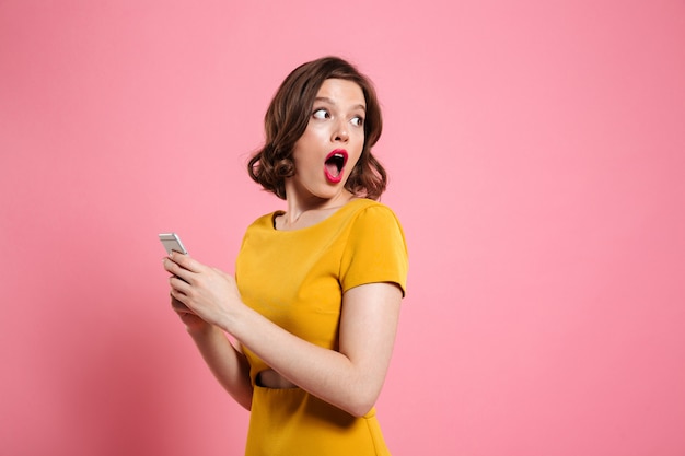 Portrait of a surprised young woman holding mobile phone