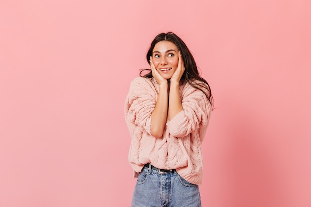 Portrait of tanned brunette girl in pink sweater in high spirits posing on isolated background.