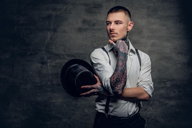 Portrait of a tattooed male wearing white shirt and suspenders.