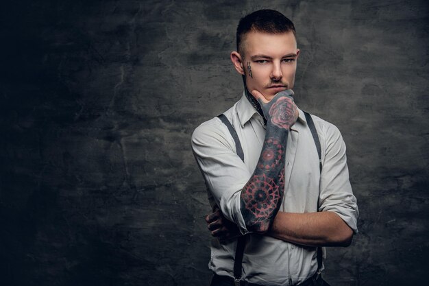 Portrait of a tattooed male wearing white shirt and suspenders.