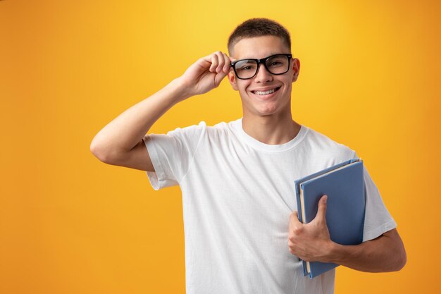 Portrait of a teen boy smiling against yellow background