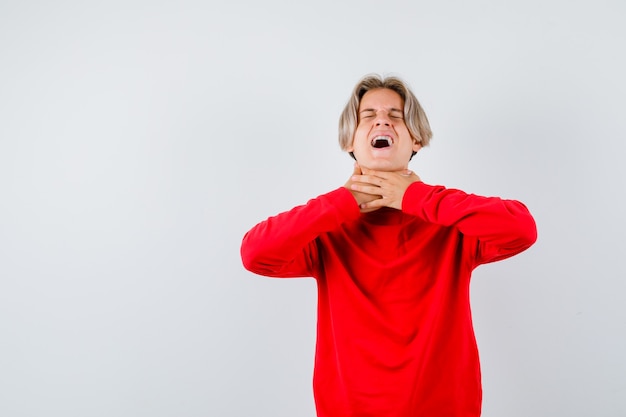 Portrait of teen boy suffering from sore throat in red sweater and looking sick front view