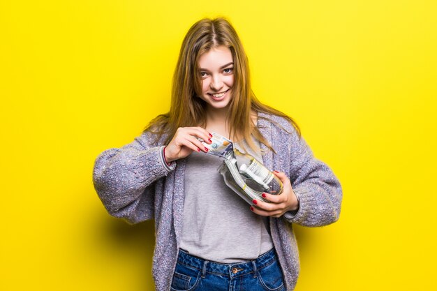 Portrait of a teen brunette girl with cuppingglass money isolated. Pot with money in teenage hands