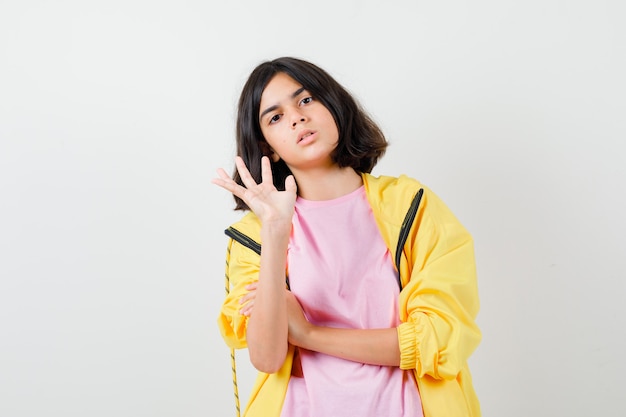 Портрет девушки-подростка, показывающей жест стоп в футболке, куртке и раздраженный вид спереди