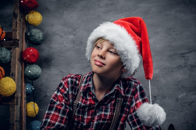 Portrait of teenage boy dressed in Santa's hat and a plaid shirt.