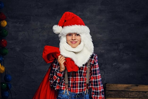 Portrait of teenage boy dressed in Santa's holiday costume and a plaid shirt.