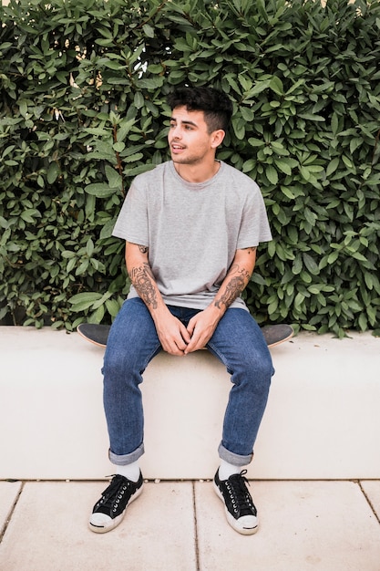 Portrait of a teenage boy sitting on skateboard