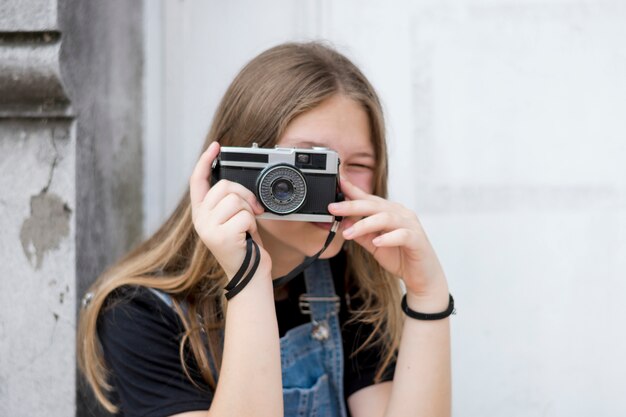 カメラで彼女の顔を覆っている10代の女性写真家の肖像画