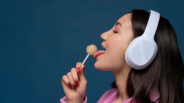 Portrait of a teenage girl listening to music  and licking a lollipop