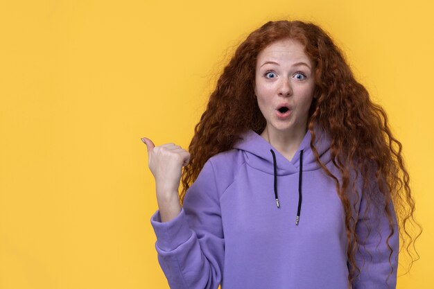 Portrait of teenage girl looking surprised and pointing to the right