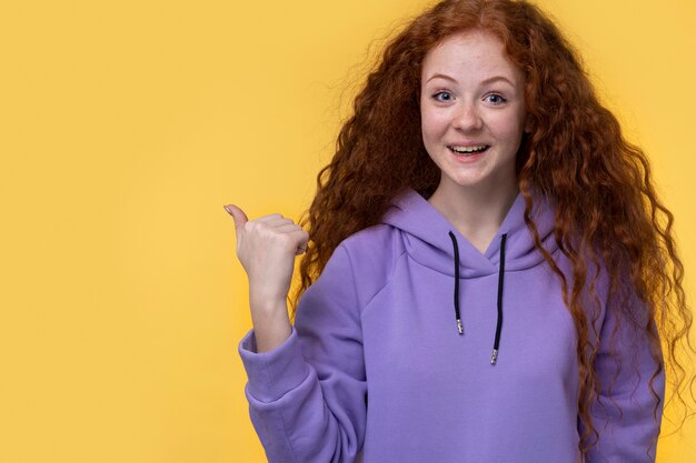 Portrait of teenage girl smiling and pointing to the right