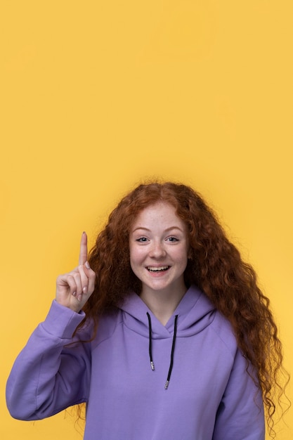 Free photo portrait of teenage girl smiling and pointing up