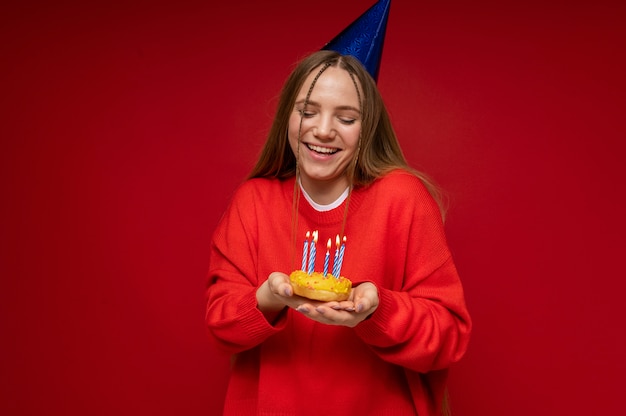 誕生日の帽子をかぶって、誕生日のキャンドルでドーナツを保持している10代の少女の肖像画