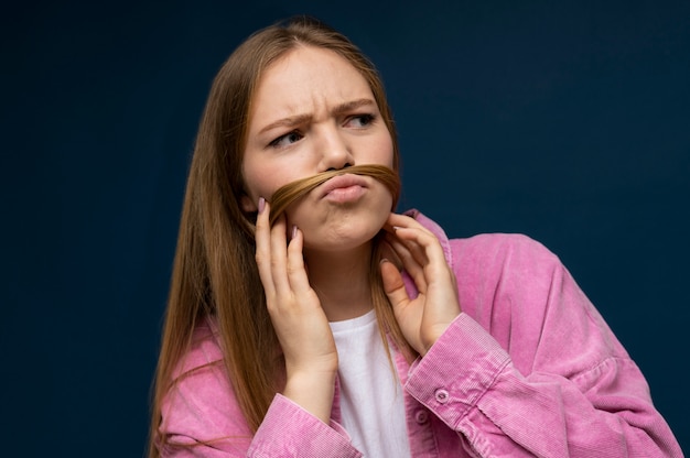 Portrait of a teenage girl with a fake moustache made out of her hair