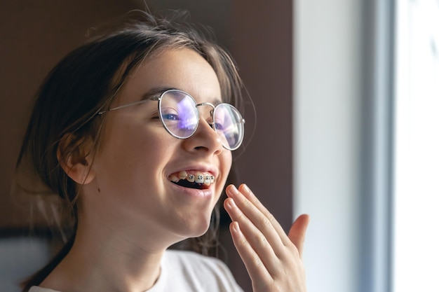 Foto gratuita ritratto di una ragazza adolescente con gli occhiali e l'apparecchio dentale