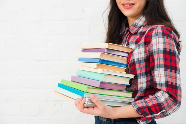 Portrait of teenage girl with stack of books